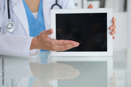 Female doctor pointing into tablet computer, close-up of hands. Physician ready to examine and help patient. Medicine, healthcare and help concept
