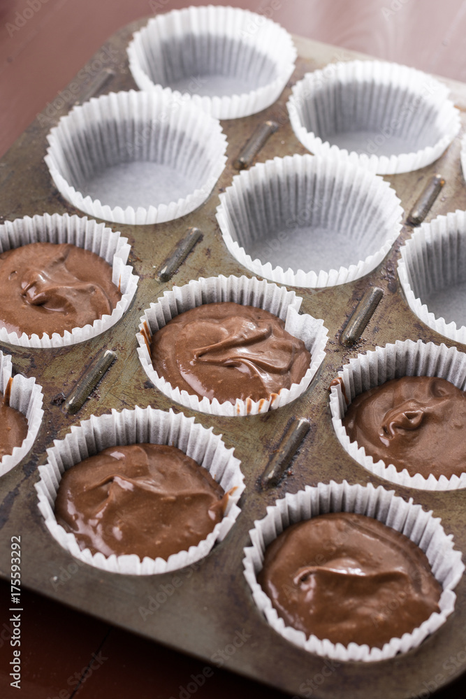 Raw chocolate cup cakes mixture in the cup cakes papers ready for baking Raw chocolate cup cakes mixture in the cup cakes papers ready for baking
