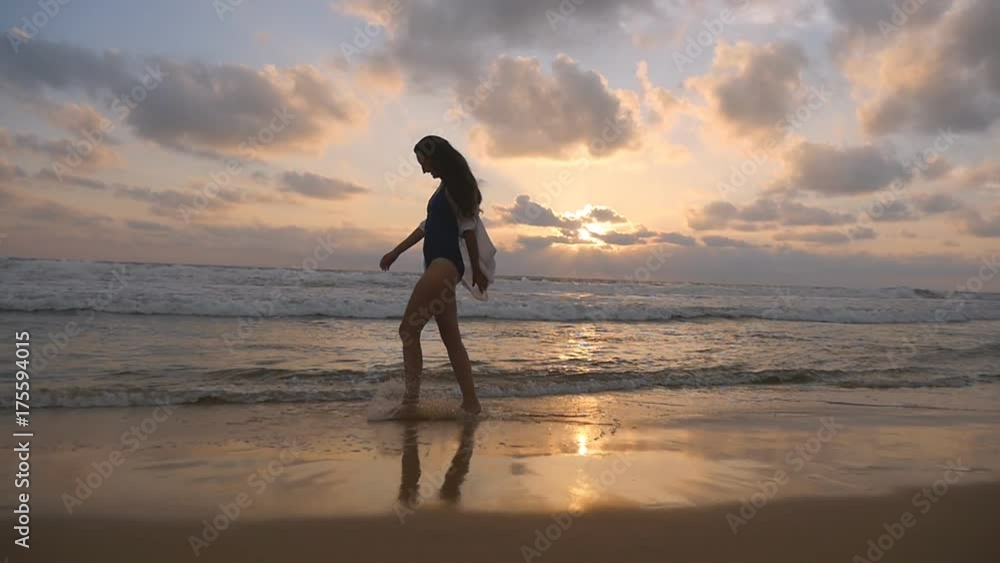 Happy woman walking and spinning on the beach near the ocean. Young beautiful girl enjoying life and having fun at sea shore. Summer vacation or holiday. Sunset landscape at background. Slow motion Happy woman walking and spinning on the beach near the ocean. Young beautiful girl enjoying life and having fun at sea shore. Summer vacation or holiday. Sunset landscape at background. Slow motion