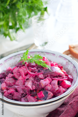 German traditional salad with beets, apple, egg and herring in a bowl, selective focus