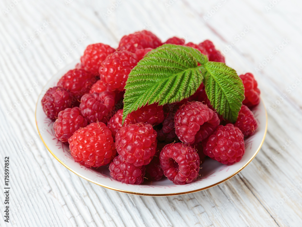 Raspberries in a bowl on a wooden white table Raspberries in a bowl on a wooden white table