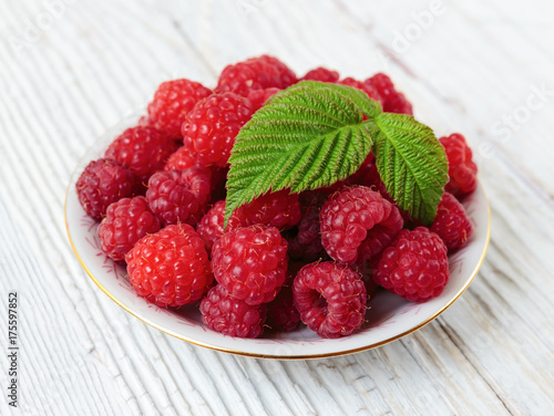 Raspberries in a bowl on a wooden white table