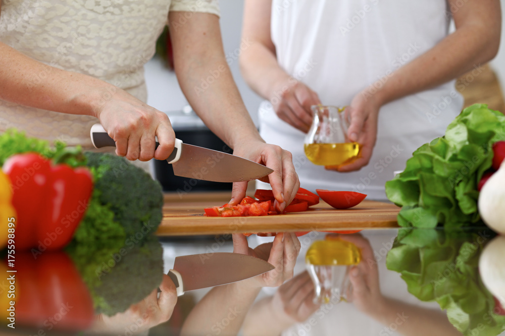 Close-up of human hands cooking in a kitchen. Friends having fun while preparing fresh salad. Vegetarian, healthy meal and friendship concept Close-up of human hands cooking in a kitchen. Friends having fun while preparing fresh salad. Vegetarian, healthy meal and friendship concept