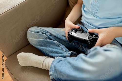 little boy with gamepad playing video game at home
