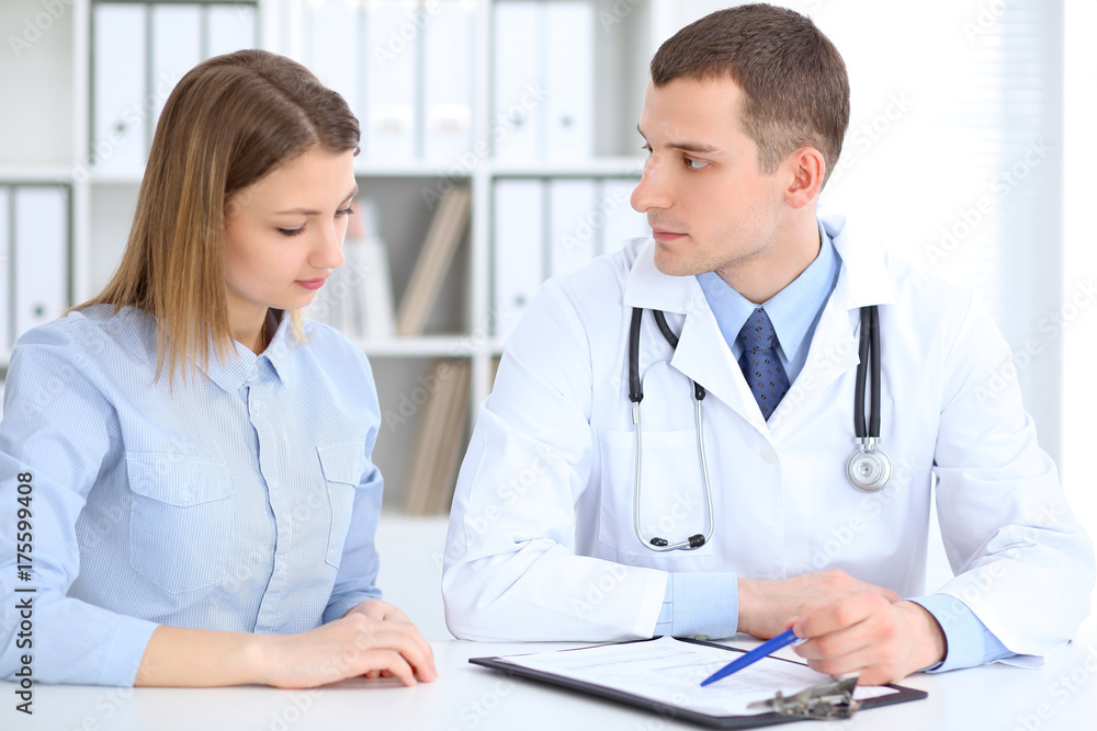 Doctor and patient sitting at the desk. Medicine and health care concept Doctor and patient sitting at the desk. Medicine and health care concept