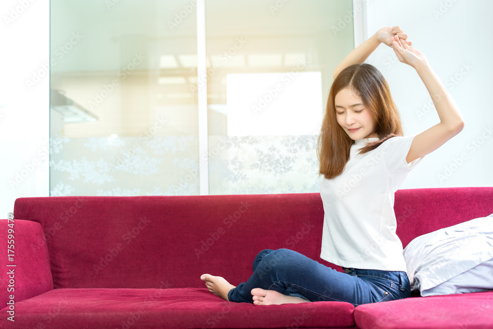 Young asian beautiful woman sitting relaxing freetime in the morning on red couch sofa living room at home