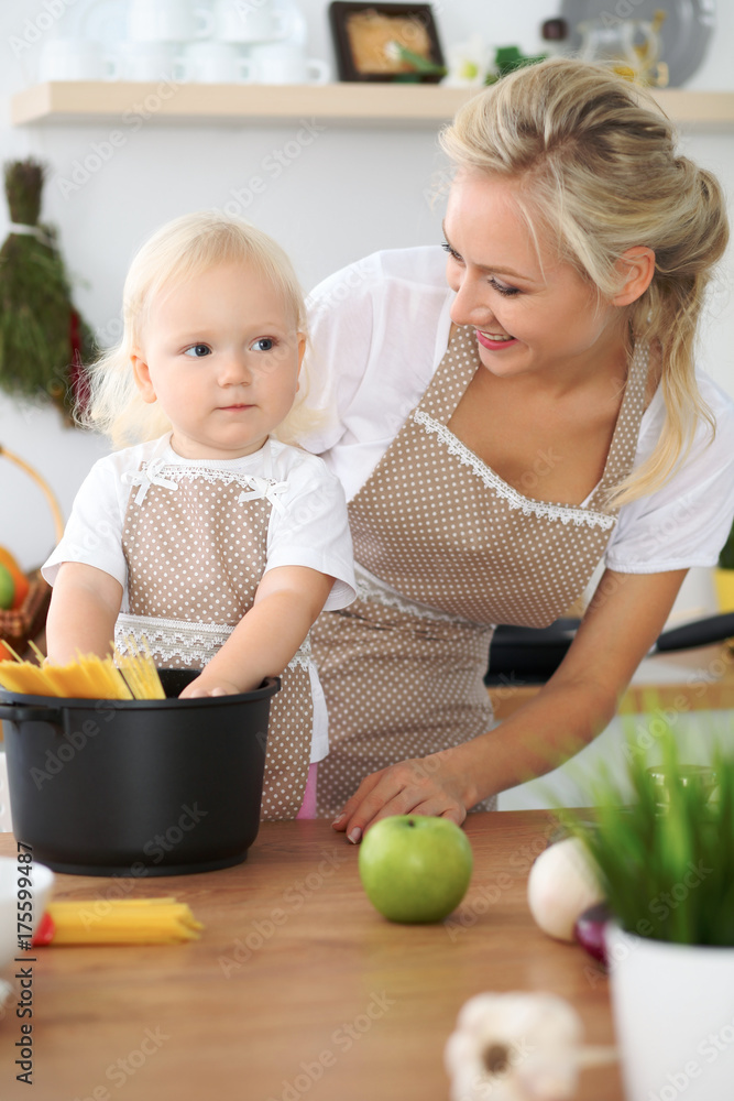 Mother and little daughter are cooking in the kitchen. Spending time all together or happy family concept Mother and little daughter are cooking in the kitchen. Spending time all together or happy family concept