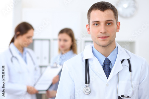 Friendly male doctor  on the background with patient  and physician