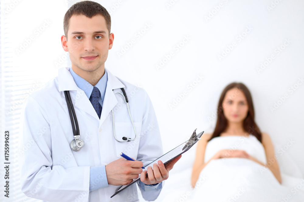 Male doctor standing on the background with patient in the bed Male doctor standing on the background with patient in the bed