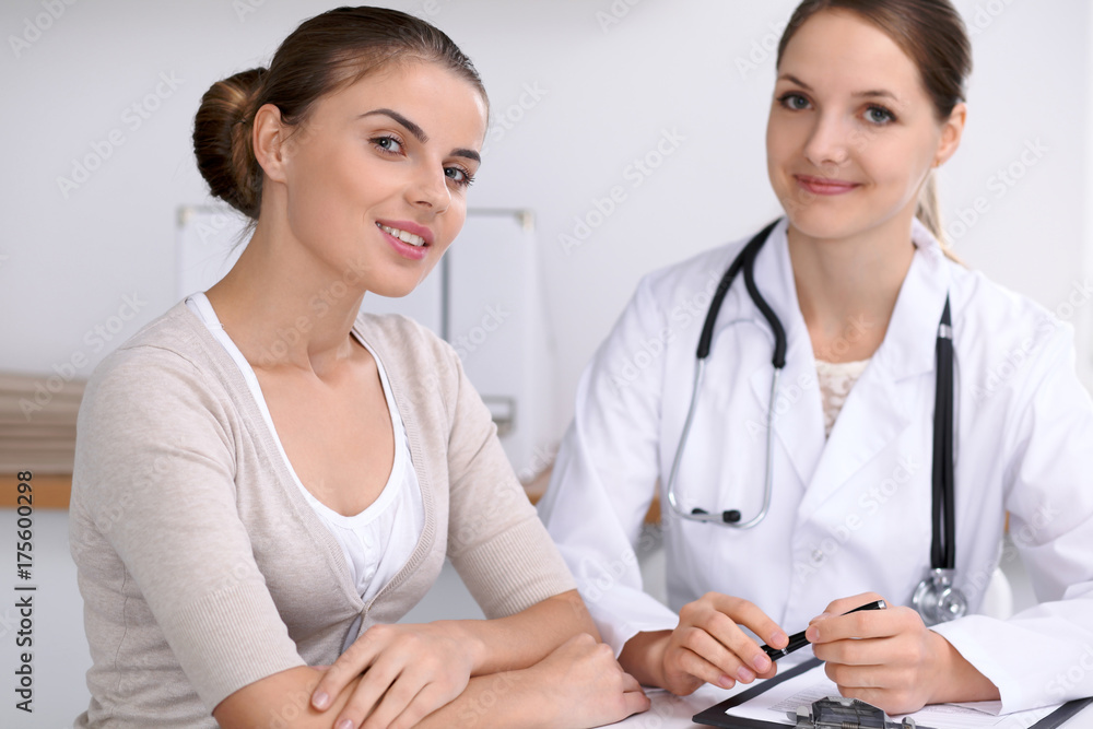 Fototapeta premium Doctor and patient sitting at the desk. The physician or therapist makes a diagnosis. Health care, medicine and patient service concept