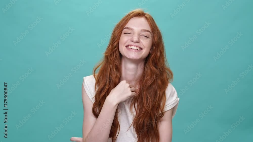 Laughing ginger woman in t-shirt looking at the camera over turquoise background Laughing ginger woman in t-shirt looking at the camera over turquoise background
