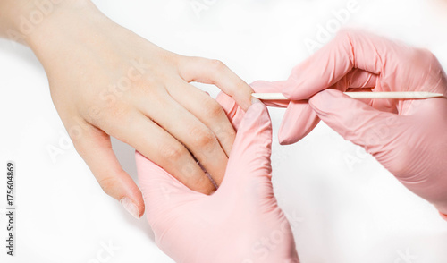 The master does a manicure to a girl. Close-up on a white background.