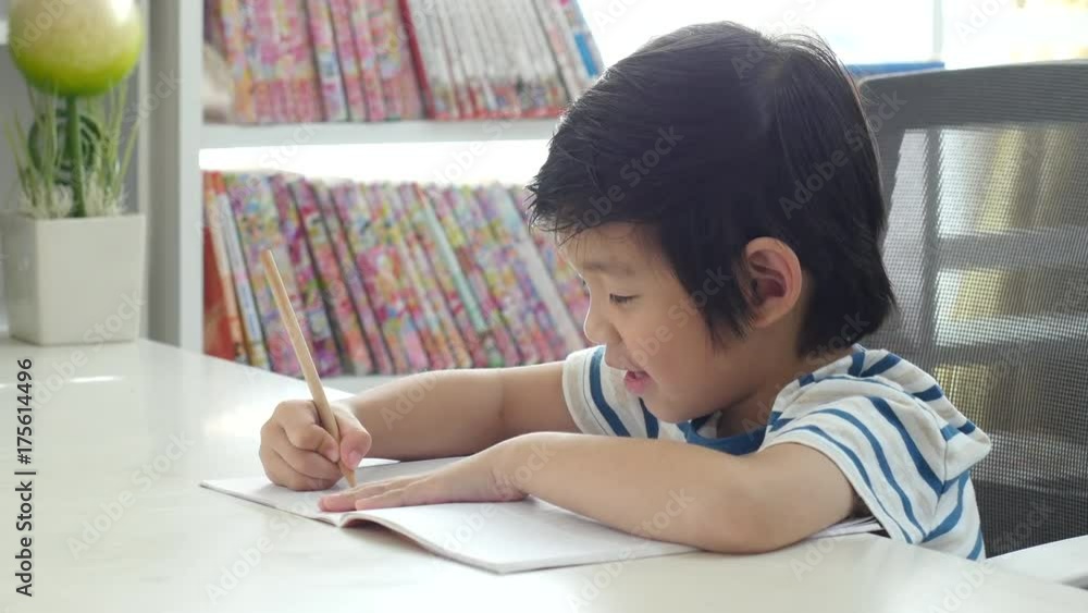 Unhappy Asian child working on hard homework at home alone Unhappy Asian child working on hard homework at home alone