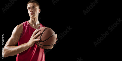 Basketball player hold a basketball ball. Isolated basketball player on a black background. Player wears unbranded clothes.