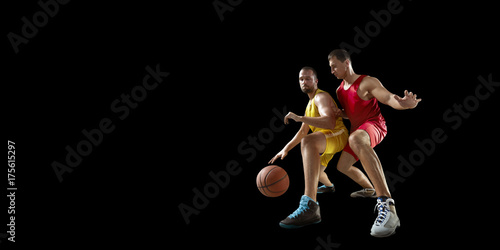 Two basketball players fight for the basketball ball. Isolated basketball players on a black background. Player wears unbranded clothes.