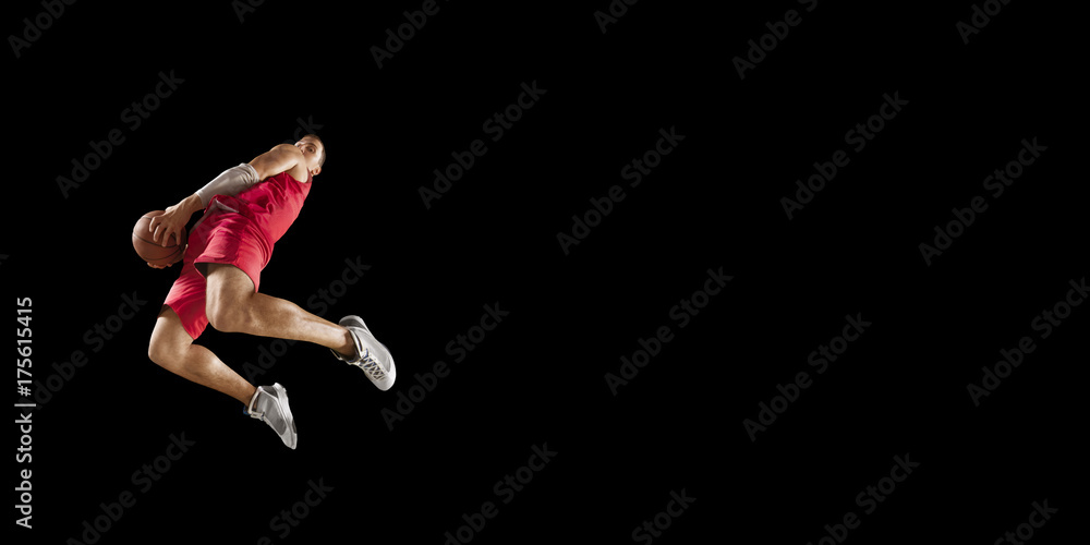 Basketball player makes slam dunk. Isolated basketball player on a black background. Player wears unbranded clothes.