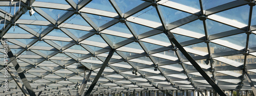 The glass ceiling of the modern building supports a steel beams grid photo