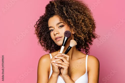 Obraz Portrait of the beautiful black woman with make-up brushes near attractive face