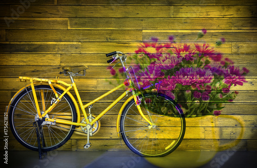 Old yellow bicycle and flower in vas on wooden background , multiply effect