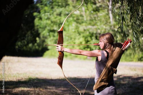 Woman taking aim with bow and arrow