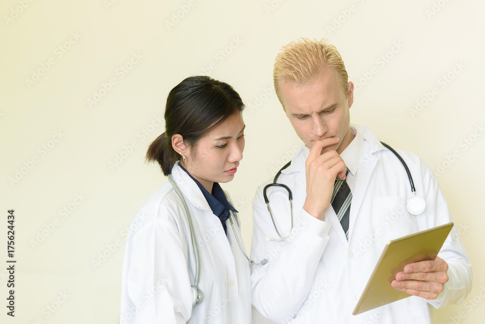 caucasian and asian doctor using digital tablet in hospital caucasian and asian doctor using digital tablet in hospital