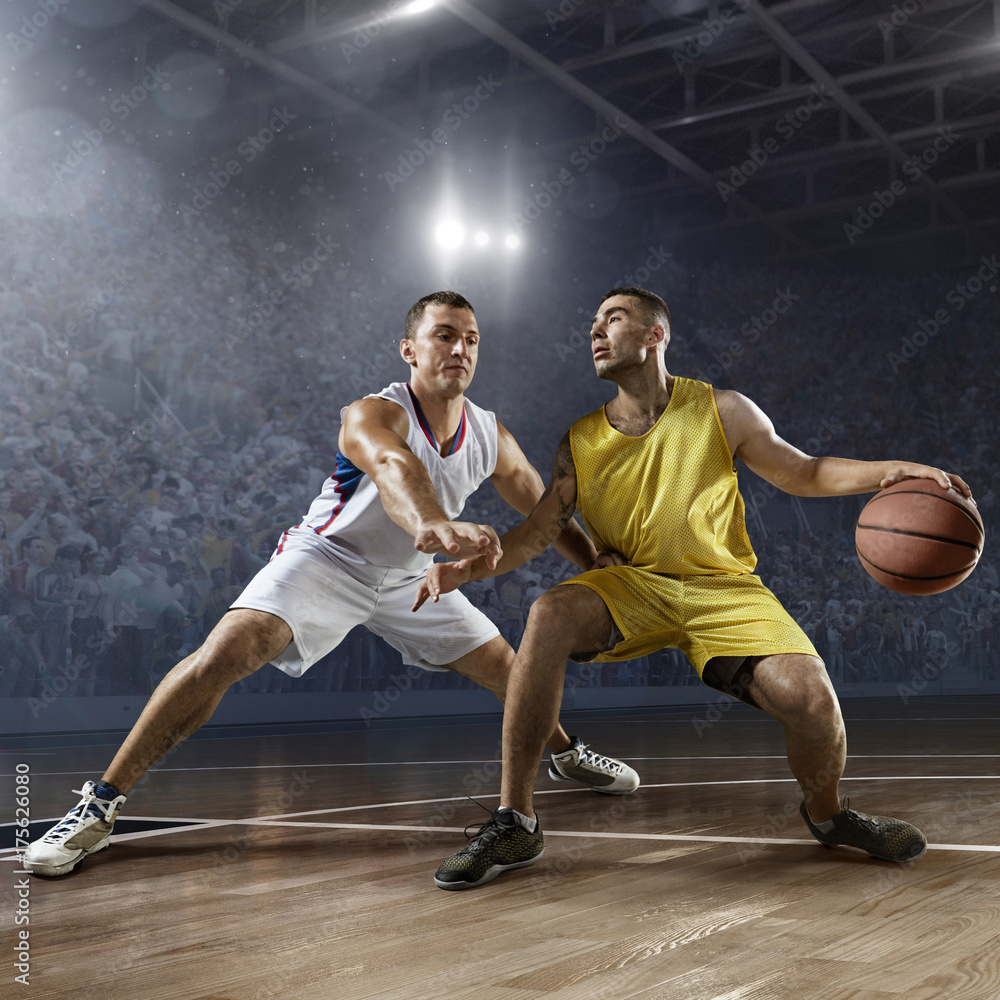 Two basketball players fight for the basketball ball on big professional arena. Player wears unbranded clothes. Two basketball players fight for the basketball ball on big professional arena. Player wears unbranded clothes.