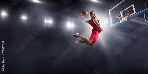 Photography Basketball player makes slam dunk on big professional arena