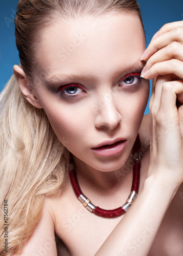 Luxury blond girl with red eyeshadow and blue eyes. Perfect skin. Stylish make-up.