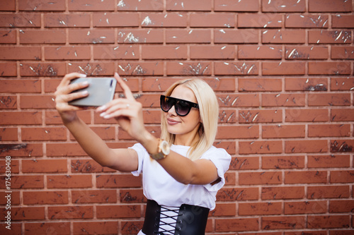 Digital composite of woman taking selfie against red brick wall photo