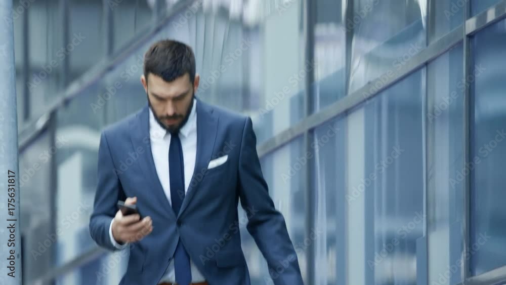 Concerned Business Man in a Hurry Uses Smartphone While Walking on the Business District Streets. Shot on RED EPIC-W 8K Helium Cinema Camera. Concerned Business Man in a Hurry Uses Smartphone While Walking on the Business District Streets. Shot on RED EPIC-W 8K Helium Cinema Camera.