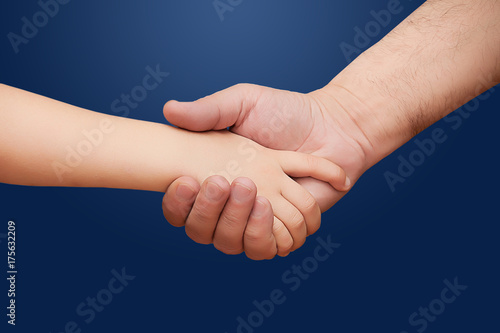 a child's hand shakes a man's adult hand