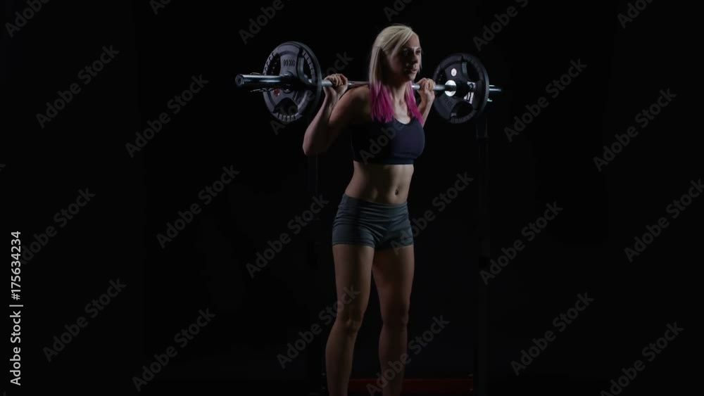 Fit young woman weight training, doing squats with barbell Fit young woman weight training, doing squats with barbell