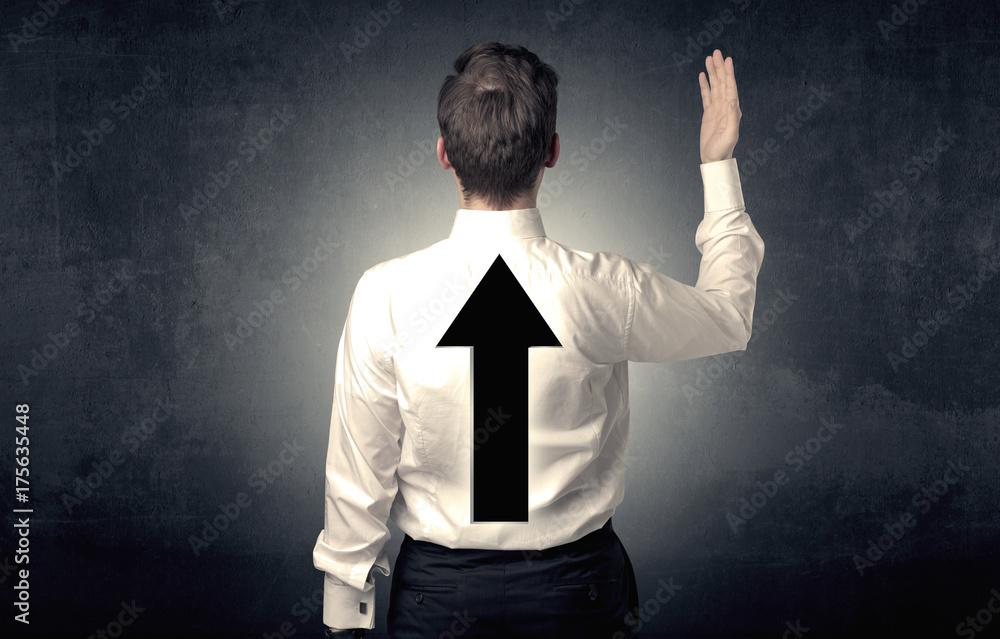 Young businessman standing with arrow on his back Young businessman standing with arrow on his back