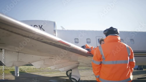  Aircraft engineers with blueprint checking over plane on the runway photo