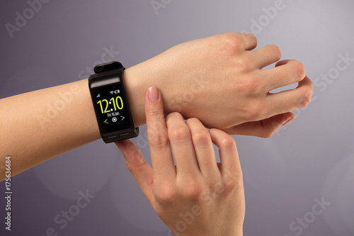 Female hand wearing and pressing smartwatch