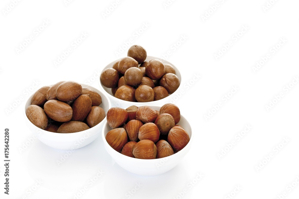 Assorted nuts in ceramic bowls, macadamia nuts, peanuts, hazelnuts Assorted nuts in ceramic bowls, macadamia nuts, peanuts, hazelnuts