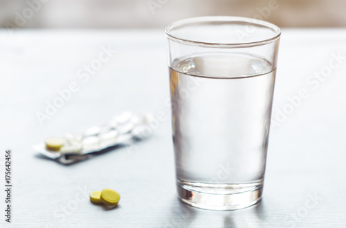 Pills, with a glass of water on a background. Treatment with medicines. 