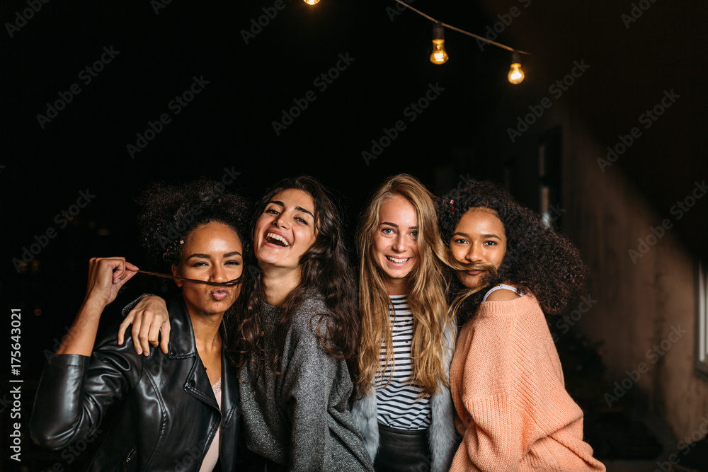 Fototapeta premium Shot of female friends having fun at night, looking at camera