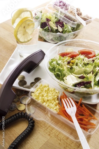 Lunch to go: Colourful salads in plastic bowls, water, phone and change photo