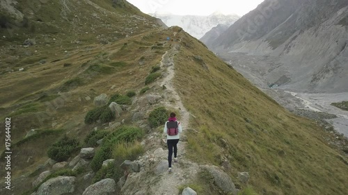 Girl walking along narrow summit ridge crest in the evening