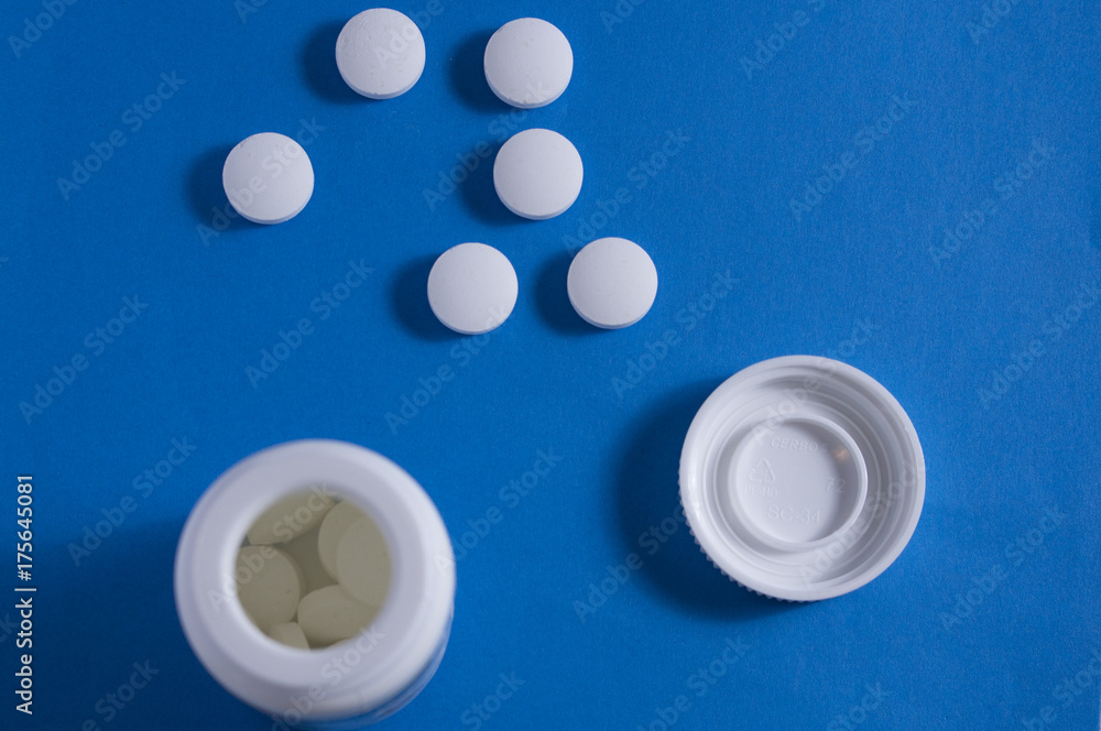 pink and white pills lying on the blue table pink and white pills lying on the blue table