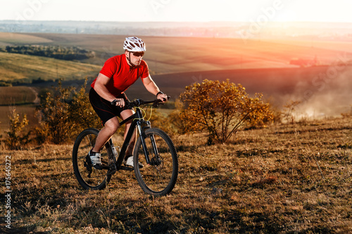 young bright man on mountain bike riding in autumn landscape