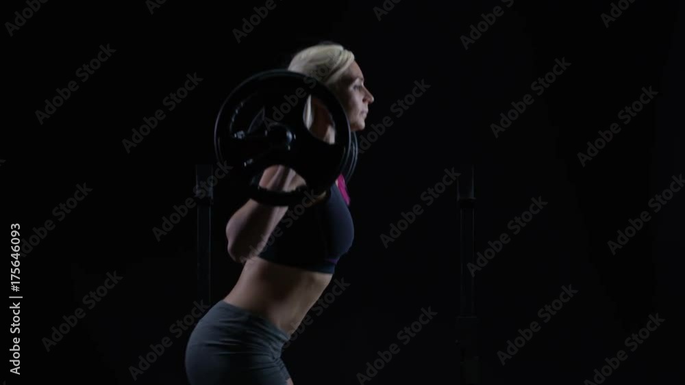  Fit young woman weight training, doing squats with barbell