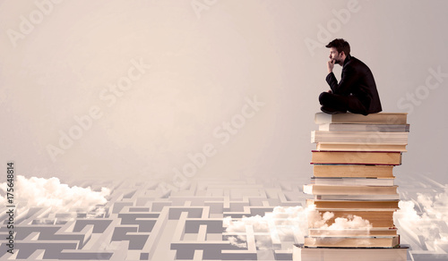 Businessman sitting on books in labirynth