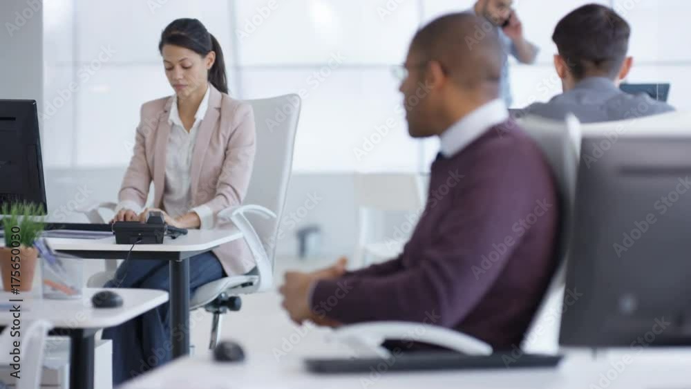 Business group in modern office working at their desks & talking Business group in modern office working at their desks & talking