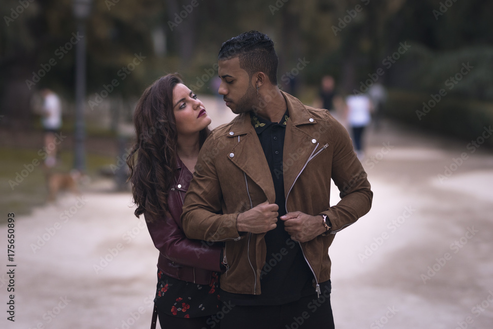 Fototapeta premium Young male and female couple hugging and looking each other in the street