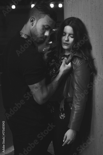 Young male and female couple hugging in the street and looking down - black and white