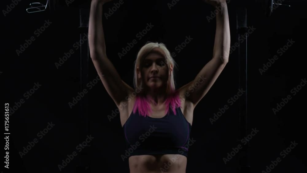 Fit young woman weight training, lifting barbell in seated position Fit young woman weight training, lifting barbell in seated position