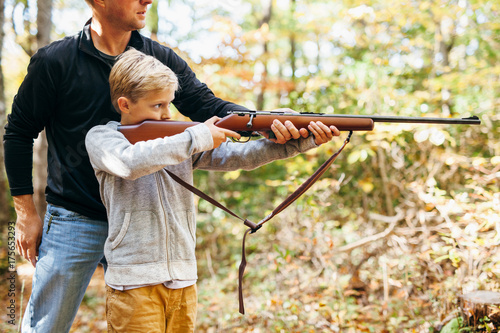 father teaching his son how to shoot a rifle photo