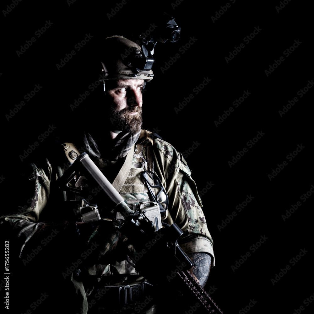 Naklejka premium Studio contour backlight shot of special forces soldier in uniforms with weapons, portrait on black background